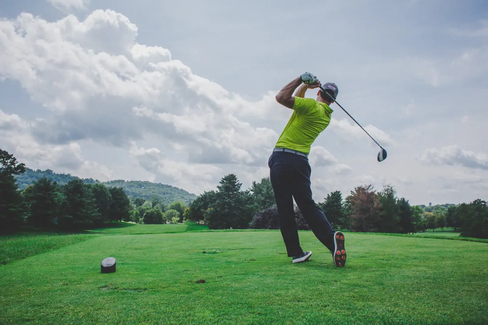 Golfista en pleno swing en el Ruitoque Golf Country Club, con las montañas al fondo